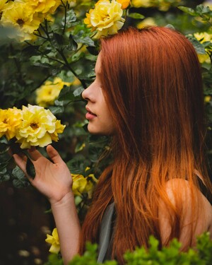 Frau mit langen roten Haaren und gelber Rose in der Hand Aveda Cherry Almond Wirkung